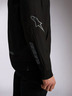 Alpinestars Sessions V3 hættetrøje, sort afslappet streetwear, nærbillede af ærme med gråt Astars-logo på albuen og ordmærke på underarmen, ribkanter, motorsport-inspireret design