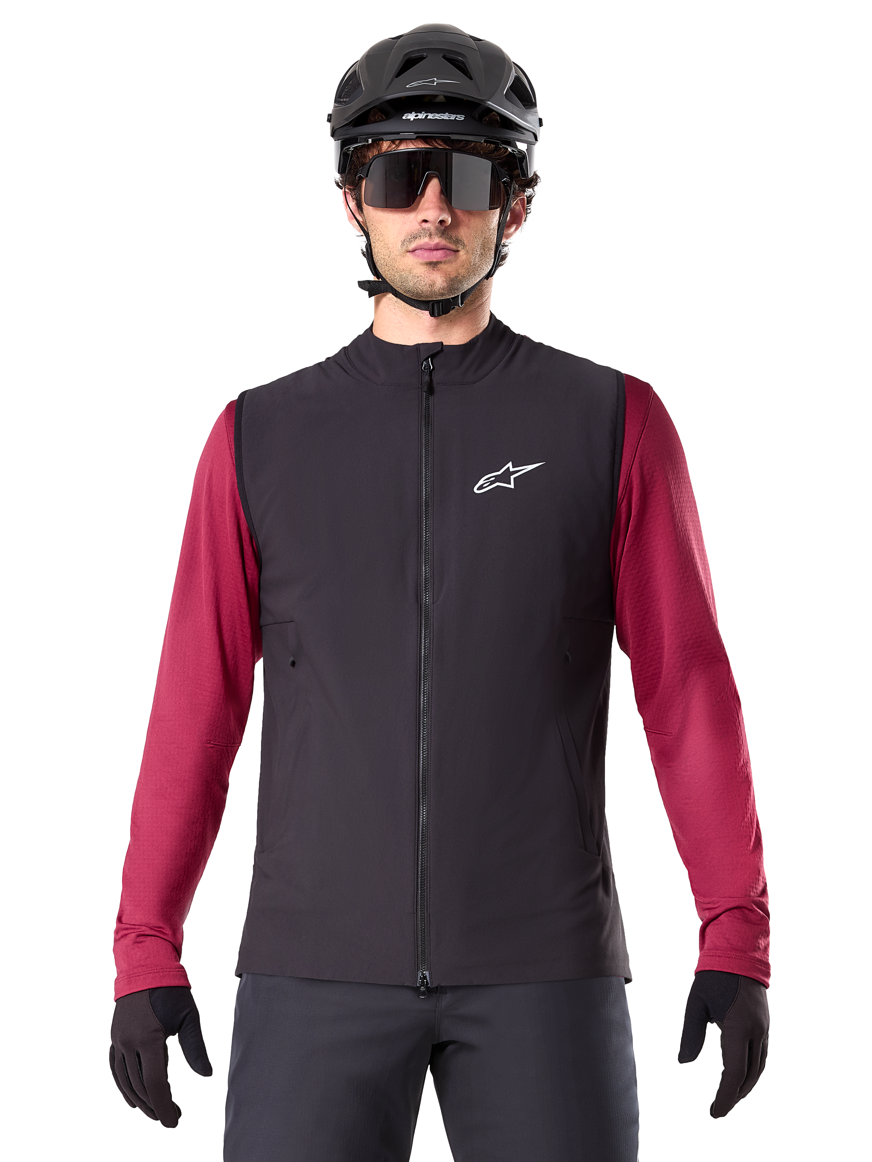 Alpinestars A-Dura Thermal Vest, sort isoleret cykelvest, båret af en model med en bordeauxrød langærmet trøje, sort MTB-hjelm og solbriller, hvidt logo på brystet, letvægts termisk beskyttelse til mountainbiking