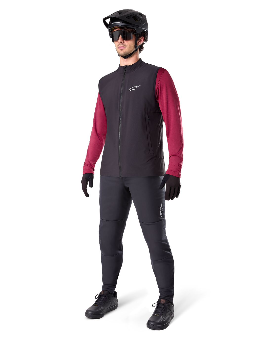 Alpinestars A-Dura Thermal Vest, sort cykelvest, bæres af en rytter over en mørkerød langærmet trøje og sorte bukser, med sort MTB-hjelm og handsker, designet til mountainbiking i koldt vejr
