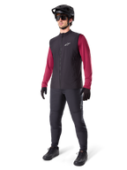 Alpinestars A-Dura Thermal Vest, sort cykelvest, bæres af en rytter over en mørkerød langærmet trøje og sorte bukser, med sort MTB-hjelm og handsker, designet til mountainbiking i koldt vejr