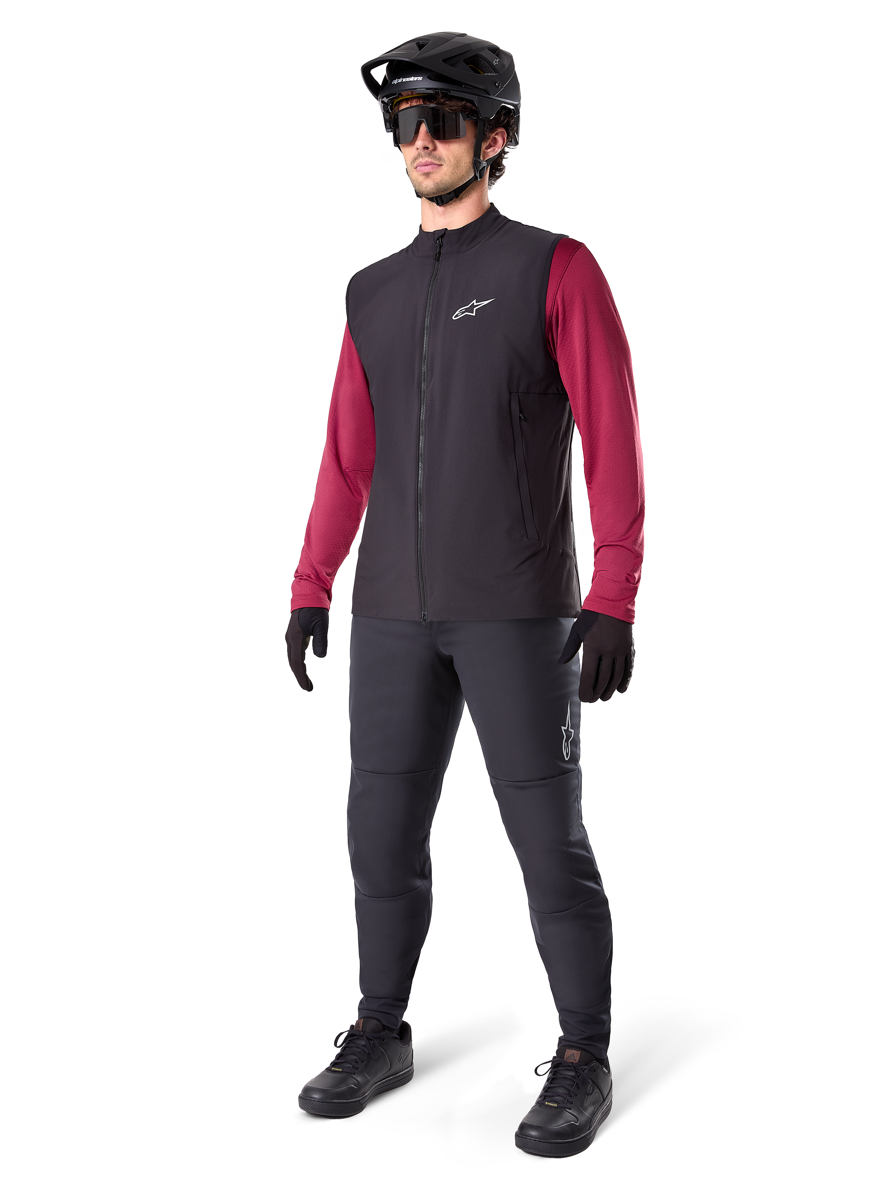 Alpinestars A-Dura Thermal Vest, sort cykelvest, bæres af en rytter over en mørkerød langærmet trøje og sorte bukser, med sort MTB-hjelm og handsker, designet til mountainbiking i koldt vejr