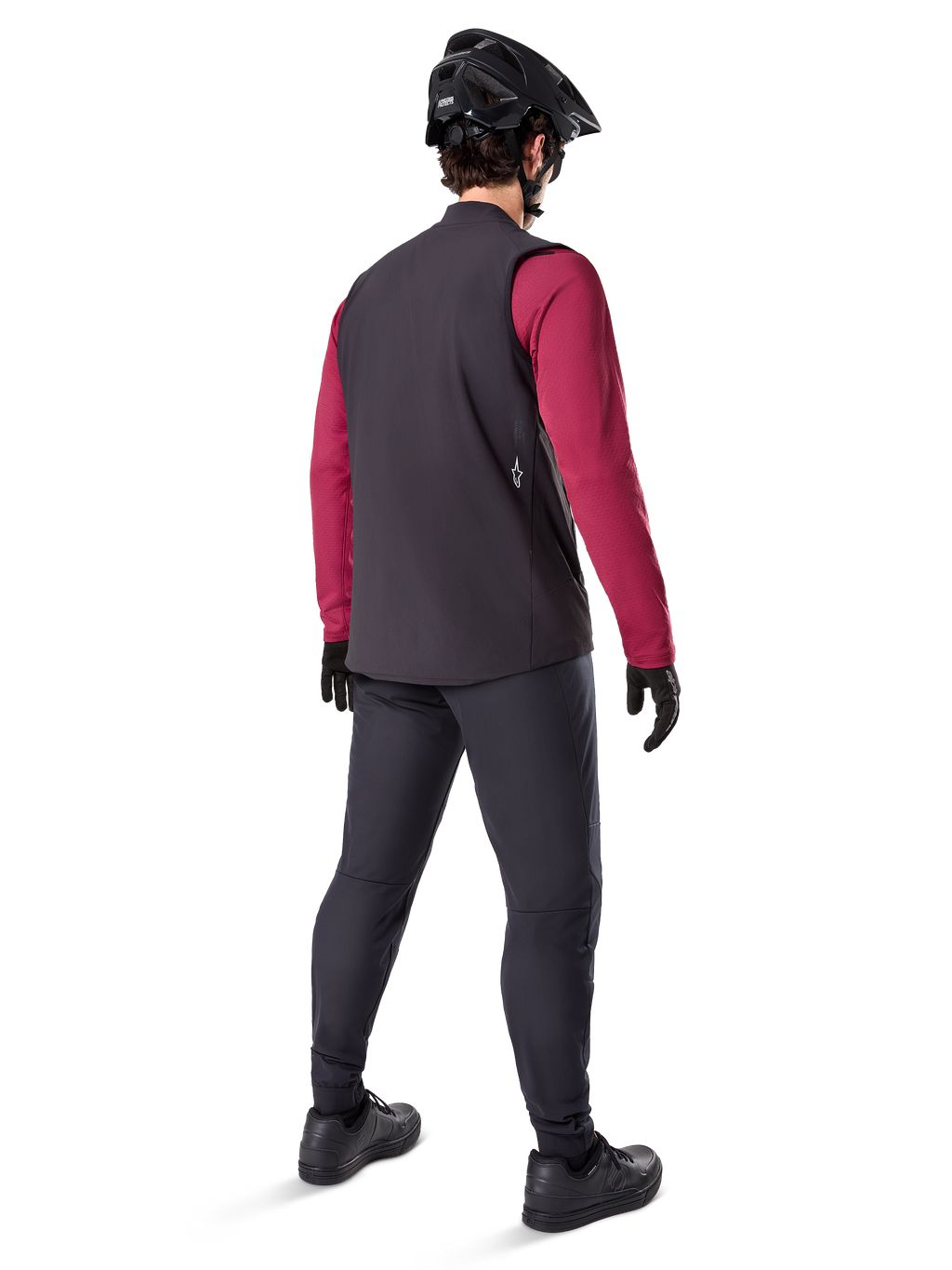 Alpinestars A-Dura Thermal Vest, sort cykelvest, set bagfra på en model iført en bordeauxrød langærmet trøje og sorte cykelbukser, kombineret med en sort mountainbikehjelm og handsker, teknisk udstyr til kørsel i koldt vejr