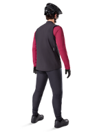Alpinestars A-Dura Thermal Vest, sort cykelvest, set bagfra på en model iført en bordeauxrød langærmet trøje og sorte cykelbukser, kombineret med en sort mountainbikehjelm og handsker, teknisk udstyr til kørsel i koldt vejr