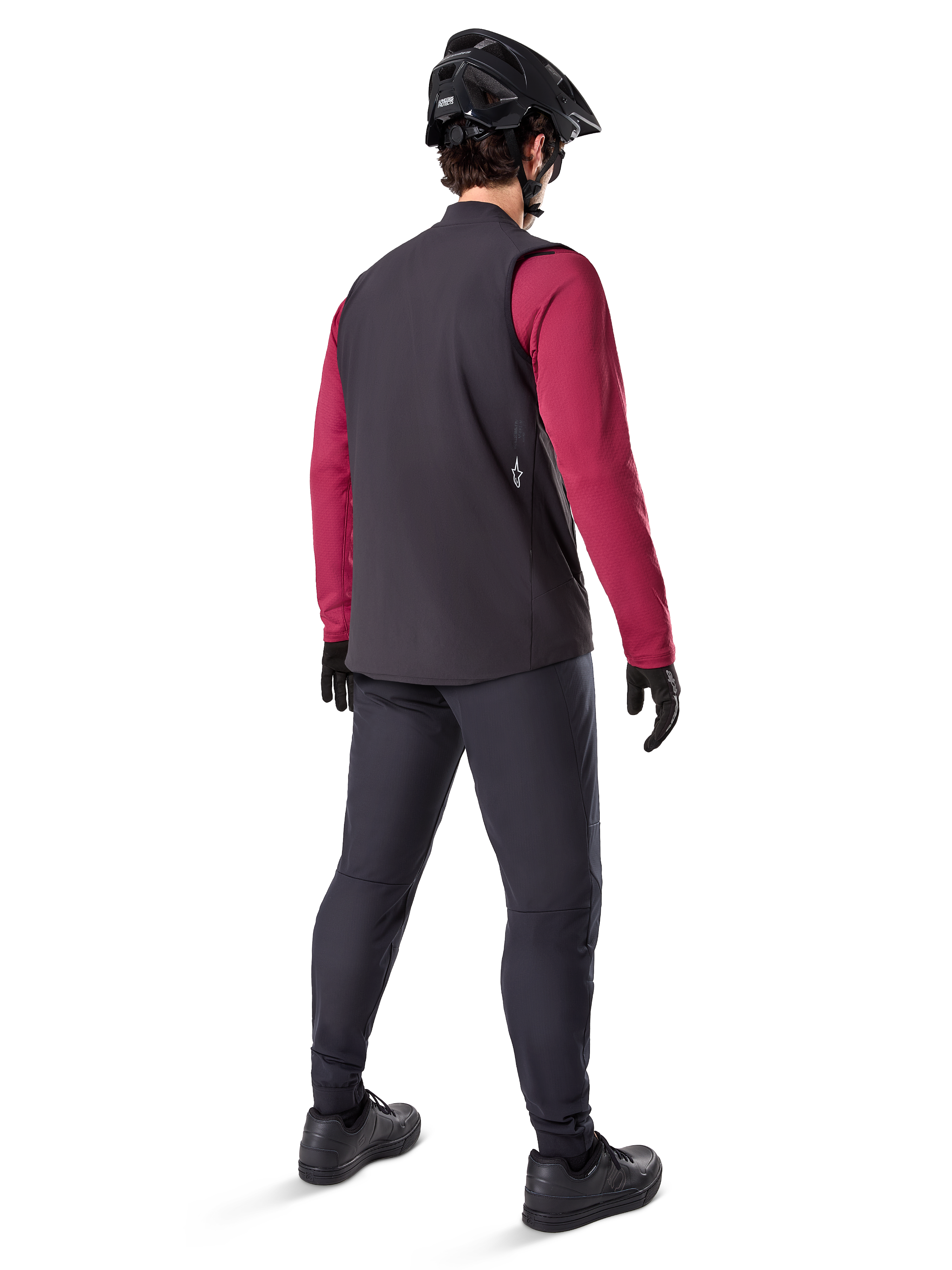 Alpinestars A-Dura Thermal Vest, sort cykelvest, set bagfra på en model iført en bordeauxrød langærmet trøje og sorte cykelbukser, kombineret med en sort mountainbikehjelm og handsker, teknisk udstyr til kørsel i koldt vejr