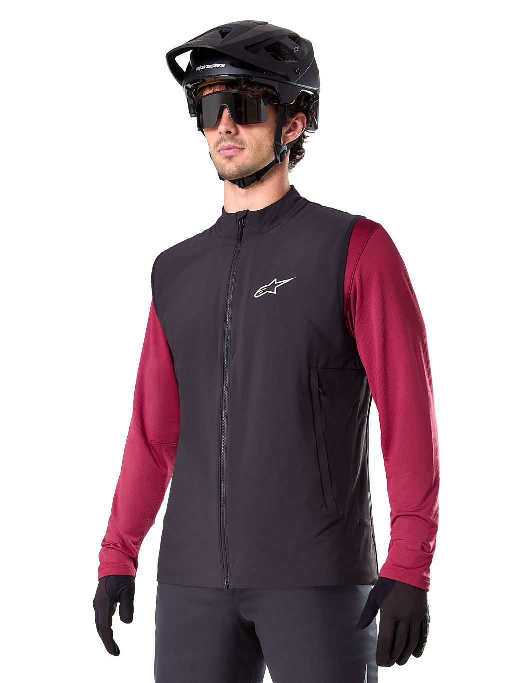 Alpinestars A-Dura Thermal Vest, sort termisk cykelvest, bæres over en vinrød langærmet trøje, med hvidt logo på brystet, kombineret med en sort MTB-hjelm og solbriller, isolerende præstationslag til mountainbiking