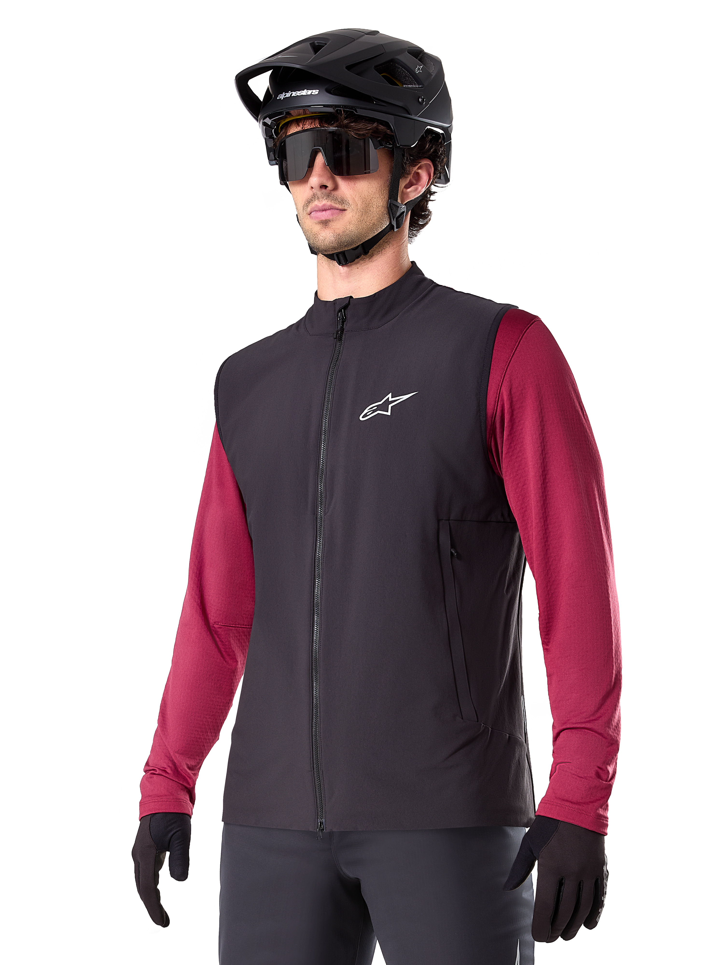 Alpinestars A-Dura Thermal Vest, sort termisk cykelvest, bæres over en vinrød langærmet trøje, med hvidt logo på brystet, kombineret med en sort MTB-hjelm og solbriller, isolerende præstationslag til mountainbiking