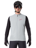 Alpinestars A-Dura Thermal Vest, cykelvest, Titanium Gray, båret med en sort langærmet trøje og sort cykelhjelm, rødt Alpinestars stjerne-logo på brystet, letvægts og isoleret til mountainbiking