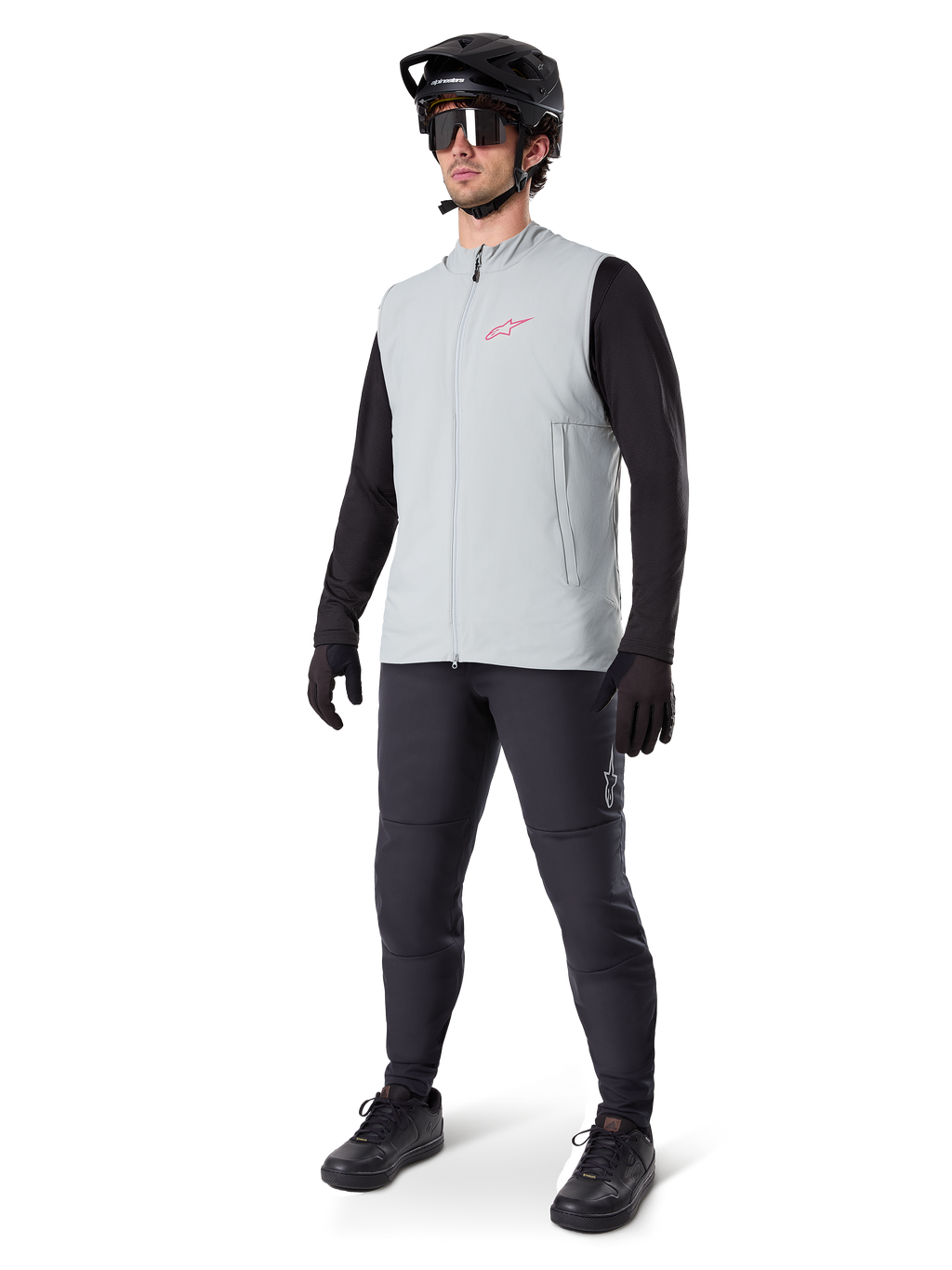 Alpinestars A-Dura termovest, titaniumgrå cykelvest med et lyserødt logo, båret af en model med en sort langærmet trøje, mørkegrå bukser og en sort mountainbikehjelm, performance-udstyr til kørsel i koldt vejr