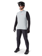 Alpinestars A-Dura termovest, titaniumgrå cykelvest med et lyserødt logo, båret af en model med en sort langærmet trøje, mørkegrå bukser og en sort mountainbikehjelm, performance-udstyr til kørsel i koldt vejr