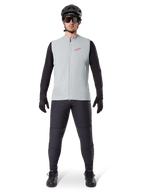 Alpinestars A-Dura Termovest, cykelvest, Titanium Gray, båret med sort langærmet trøje og sorte bukser, sort hjelm og solbriller, med et rødt Alpinestars-logo, letvægts termisk isolering til mountainbike