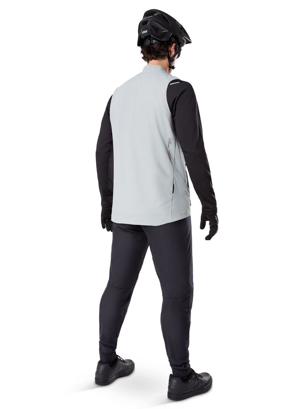 Alpinestars A-Dura Thermal Vest, Titanium Gray, set bagfra af model iført den isolerede cykelvest over en sort langærmet trøje og mørke bukser, komplet med en sort mountainbikehjelm og handsker, designet til terrænkørsel i koldt vejr