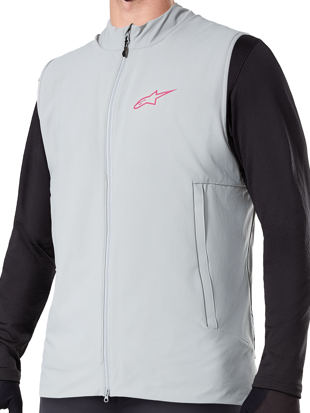 Alpinestars A-Dura termovest, titaniumgrå isoleret cykelvest, lyserødt stjernelogo på brystet, båret over en sort langærmet trøje, lodret lynlåslomme og gennemgående lynlås foran, designet til mountainbike-kørsel i koldt vejr