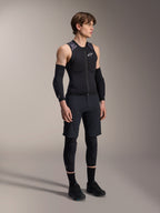 Alpinestars A-Motion Plasma beskyttelsesvest, ærmeløs sort og camo MTB-beskyttelsesvest, fuldkropsvisning af model iført vest med armærmer og knæbeskyttere, lynlås foran med hvidt Alpinestars-logo, high-performance udstyr til mountainbiking