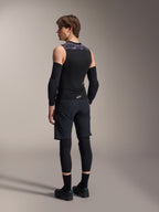 Mandlig model set bagfra iført Alpinestars A-Motion Plasma beskyttelsesvest, Black Camo, ærmeløst mesh-design med integreret rygbeskytter, gråt camouflage-mønster på skuldrene, kombineret med sorte albuebeskyttere og mountainbike-shorts, professionelt cykeludstyr