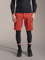 Alpinestars A-Motion Plasma knæbeskytter, sort MTB-knæbeskytter, båret med røde shorts og sort langærmet top, ergonomisk design med slank profil, letvægts mesh-konstruktion til off-road kørsel