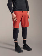 Alpinestars A-Motion Plasma knæsleeve, MTB-knæbeskytter, sort, båret med røde shorts og sorte mountainbike-sko, lavprofils slip-on-design med konturerede beskyttelsespuder og åndbart mesh.