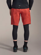 Alpinestars A-Motion Plasma knæærme, sorte MTB-knæbeskyttere, set bagfra båret under røde mountainbike-shorts med en sort jersey og tekniske cykelsko, beskyttelsesudstyr til mountainbike