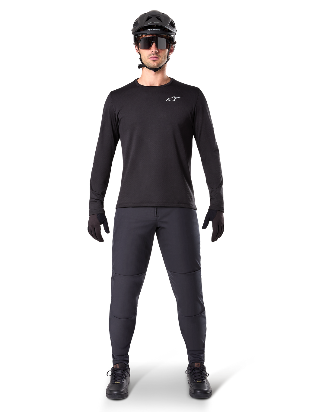 Alpinestars A-Dura termobukser, sort, båret af en rytter i komplet mountainbike-udstyr inklusiv en sort langærmet trøje, hjelm og solbriller, holdbare bukser med en almindelig pasform til kørsel på spor i koldt vejr