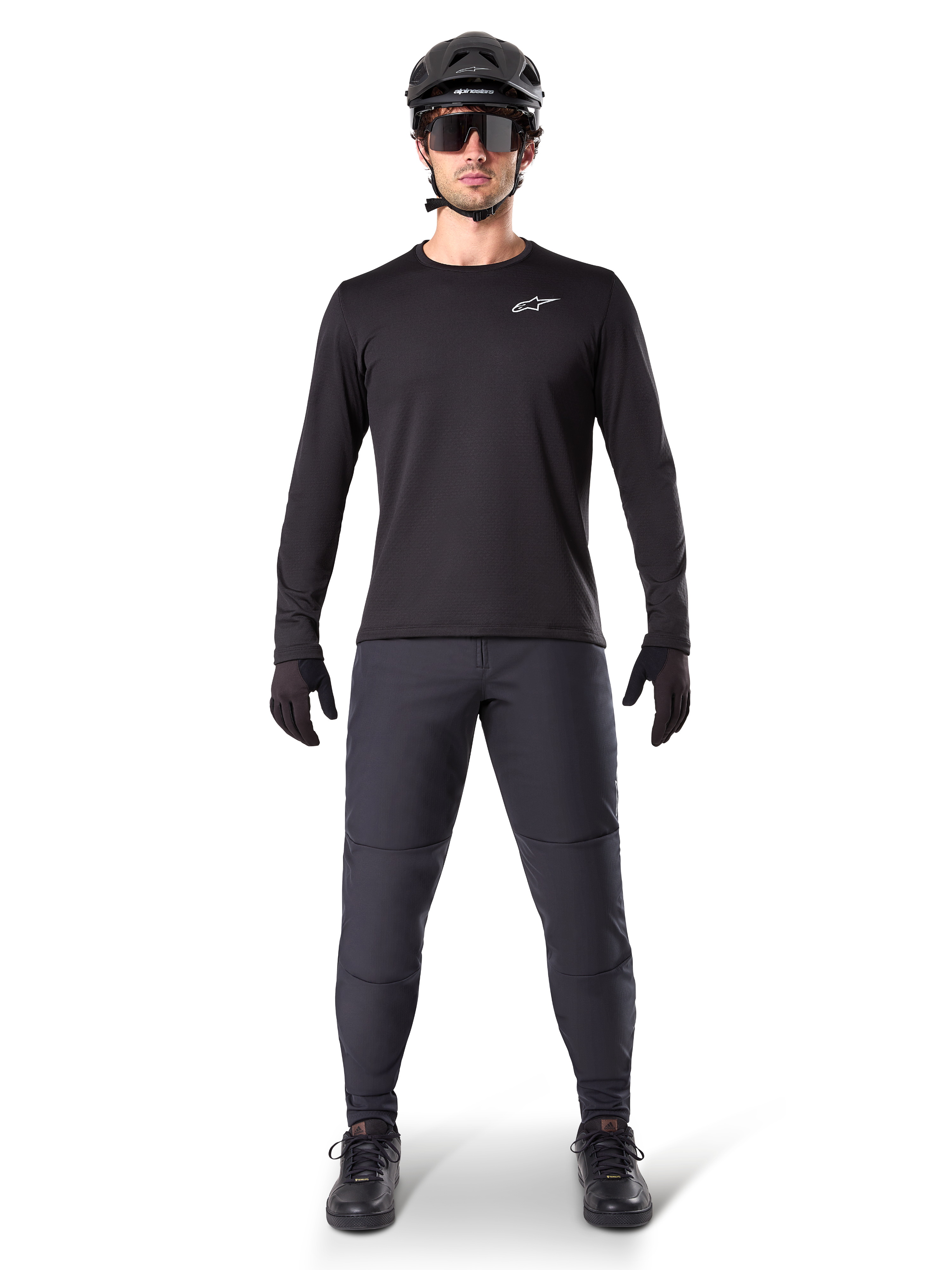 Alpinestars A-Dura termobukser, sort, båret af en rytter i komplet mountainbike-udstyr inklusiv en sort langærmet trøje, hjelm og solbriller, holdbare bukser med en almindelig pasform til kørsel på spor i koldt vejr