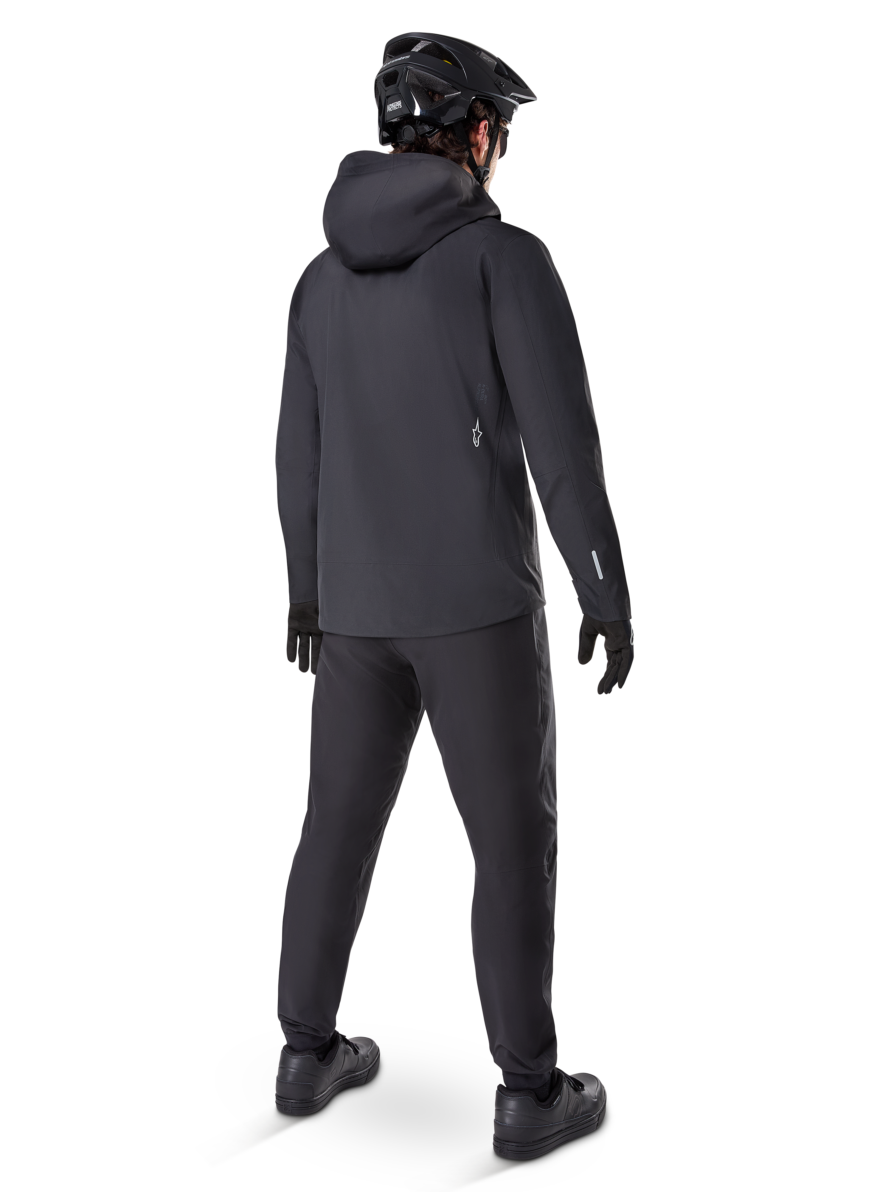 Alpinestars A-Dura Waterproof Pants, MTB-bukser, sort, set bagfra på en rytter iført et komplet sort mountainbike-outfit inklusive en jakke med hætte og hjelm, slidstærkt vandtæt udstyr til mudrede stier
