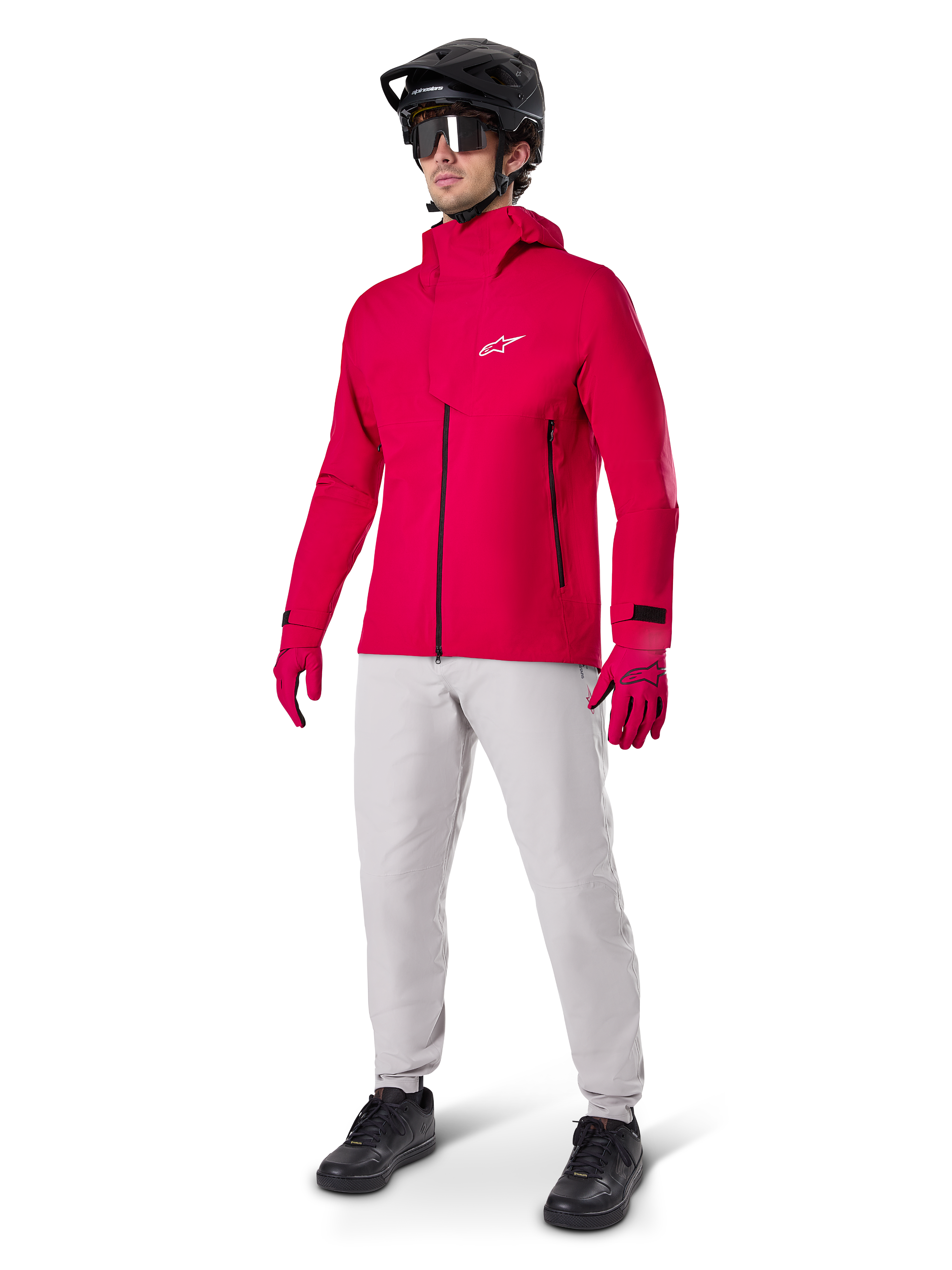 Model iført Alpinestars A-Dura vandtætte bukser i Titanium-grå, kombineret med en klar rød vandtæt jakke og matchende handsker, sort mountainbikehjelm med goggles og sorte sko, komplet mountainbike-udstyr til våde sporforhold
