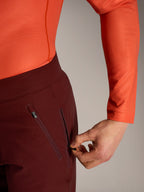 Alpinestars A-Dura Ride shorts i bordeaux, detalje af hånd der åbner en sikker sidelomme med lynlås og mesh-for.