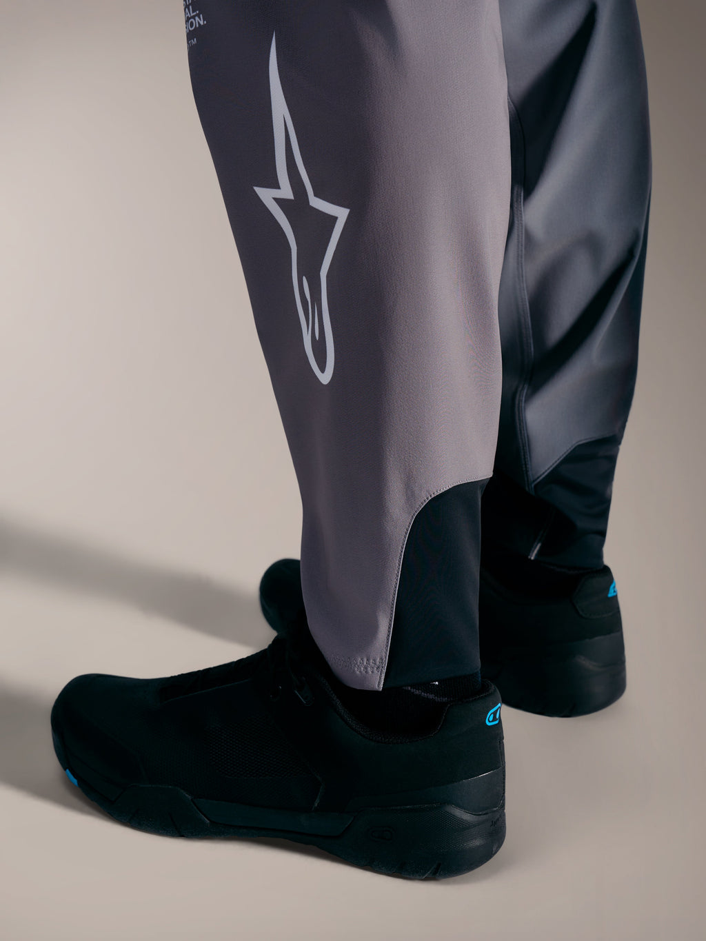 Grå A-Supra Elite Bukser med hvidt Astars-logo og strækmanchetter designet til performance MTB-racing.