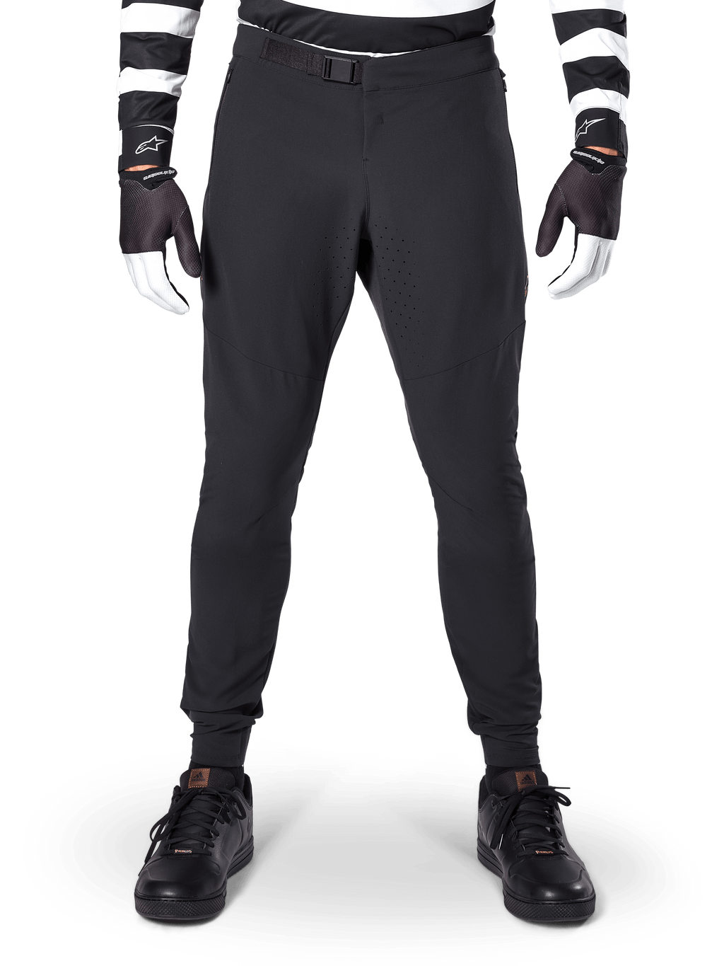 Alpinestars A-Aria Elite bukser, mountainbike-bukser, sort, set forfra med laserperforeringer og magnetisk spændelukning, bæres med en sort- og hvidstribet trøje og sorte handsker, performance-cykeludstyr til trailkørsel
