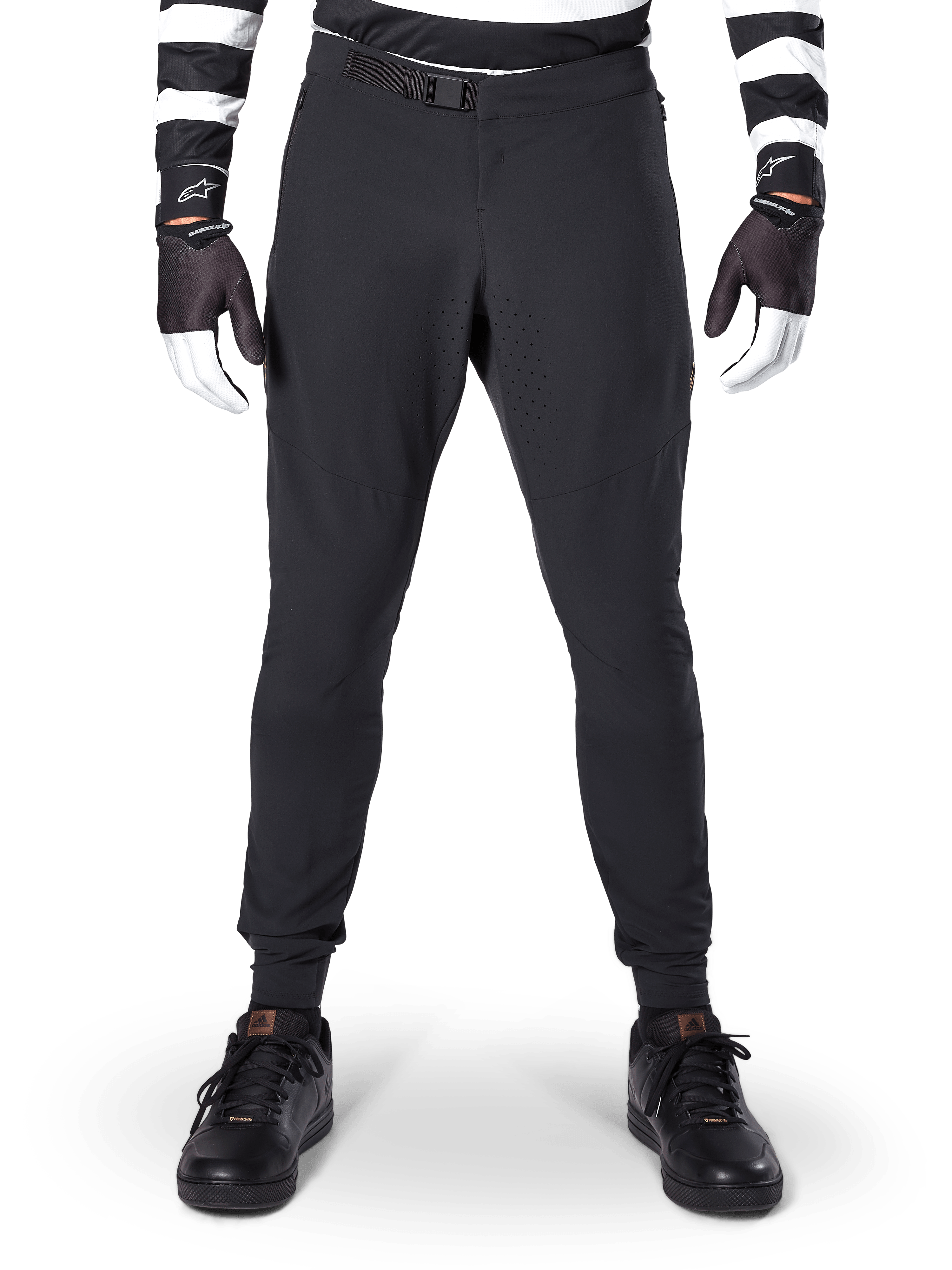 Alpinestars A-Aria Elite bukser, mountainbike-bukser, sort, set forfra med laserperforeringer og magnetisk spændelukning, bæres med en sort- og hvidstribet trøje og sorte handsker, performance-cykeludstyr til trailkørsel
