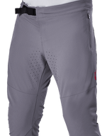Alpinestars A-Aria Elite bukser, MTB-cykelbukser, mørkegrå, nærbillede med magnetisk spændelukning, lynlåslomme i siden og laserskårne ventilationsperforeringer på indersiden af lårene til trailkørsel.