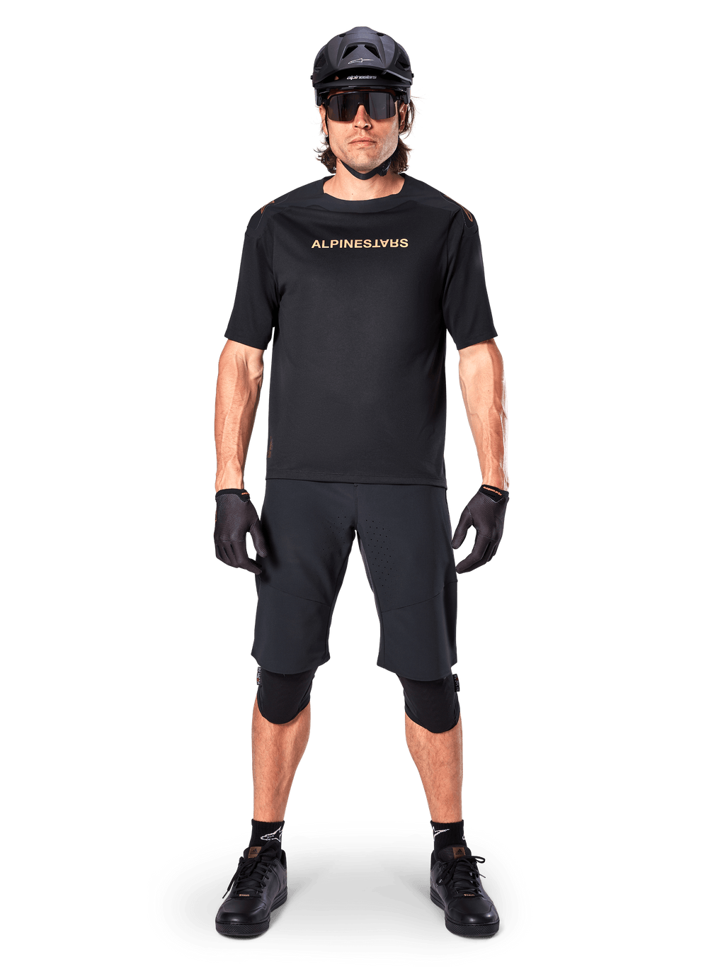 Mandlig mountainbikerytter iført Alpinestars A-Aria Elite Shorts i sort, kombineret med en matchende sort kortærmet Alpinestars trøje, sort hjelm, handsker og knæbeskyttere, komplet off-road cykeludstyr