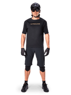 Mandlig mountainbikerytter iført Alpinestars A-Aria Elite Shorts i sort, kombineret med en matchende sort kortærmet Alpinestars trøje, sort hjelm, handsker og knæbeskyttere, komplet off-road cykeludstyr