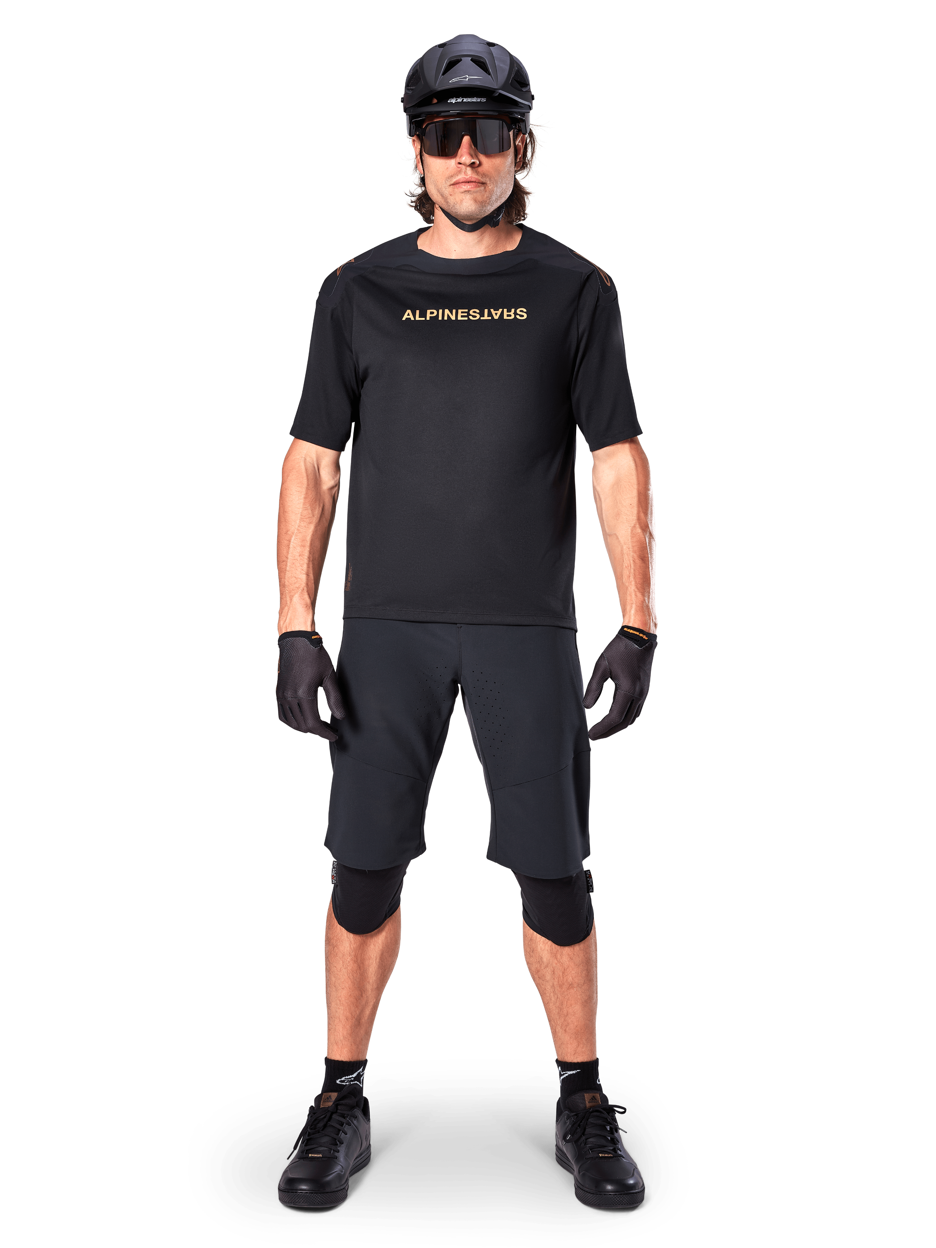 Mandlig mountainbikerytter iført Alpinestars A-Aria Elite Shorts i sort, kombineret med en matchende sort kortærmet Alpinestars trøje, sort hjelm, handsker og knæbeskyttere, komplet off-road cykeludstyr
