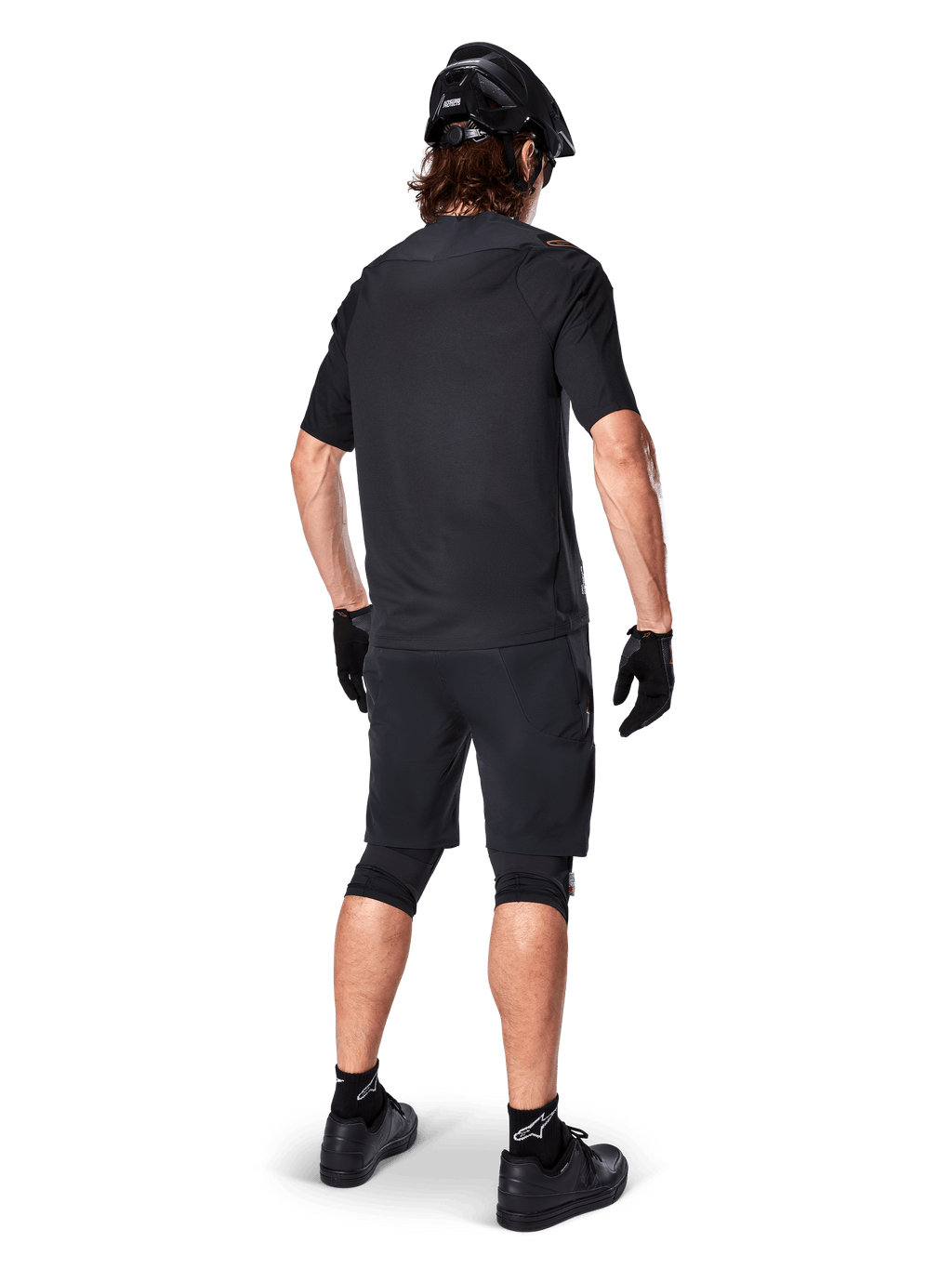Set bagfra af en mountainbiker iført Alpinestars A-Aria Elite Shorts i sort, kombineret med en matchende sort kortærmet jersey, sort hjelm, handsker og MTB-sko, der viser et komplet performance-outfit til off-road cykling.
