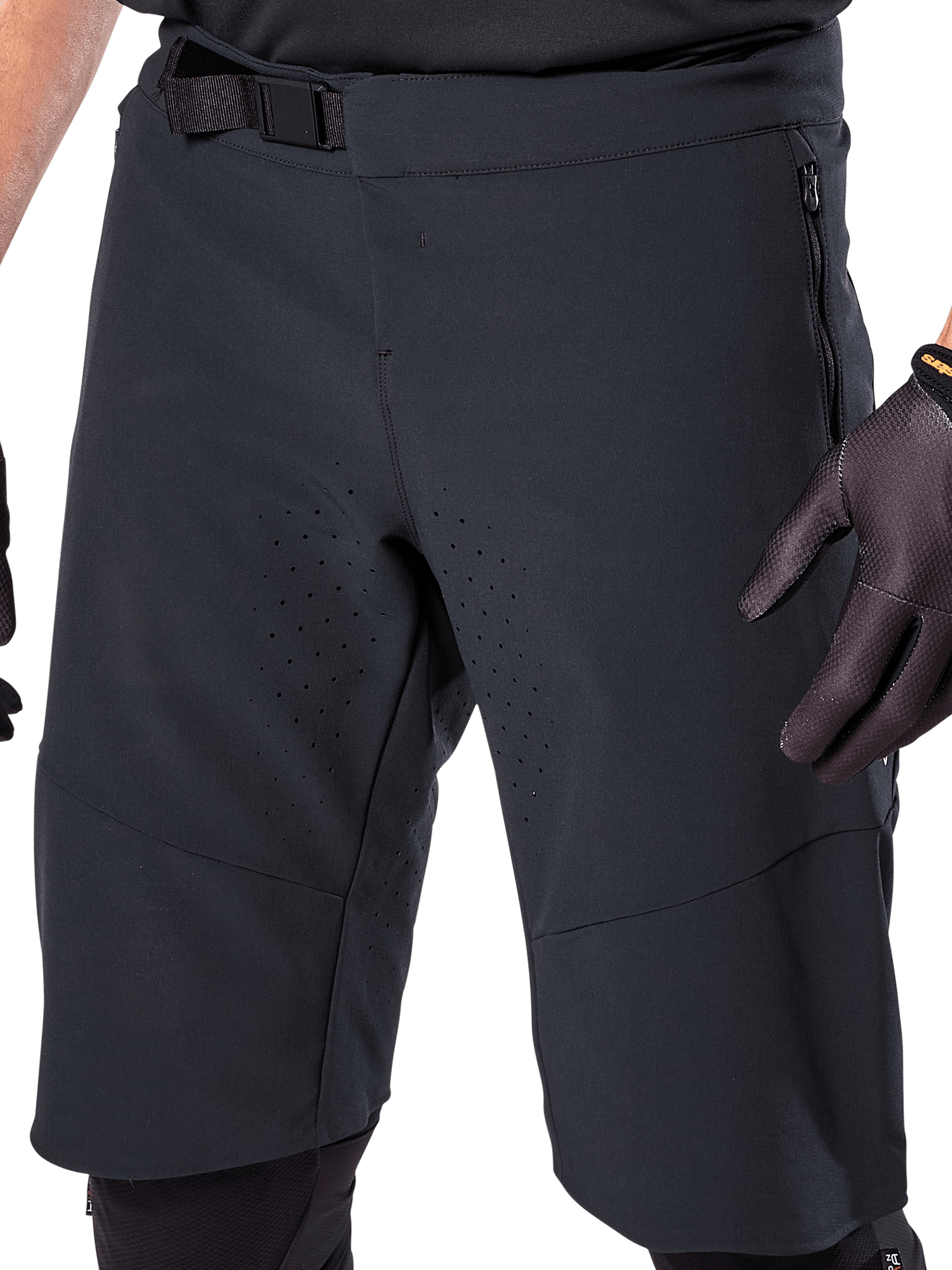 Alpinestars A-Aria Elite Shorts i sort, nærbillede af talje- og lårområdet, med magnetisk spændelukning, lynlåslommer og laserskårne ventilationsperforeringer, båret med sorte cykelhandsker til mountainbike.