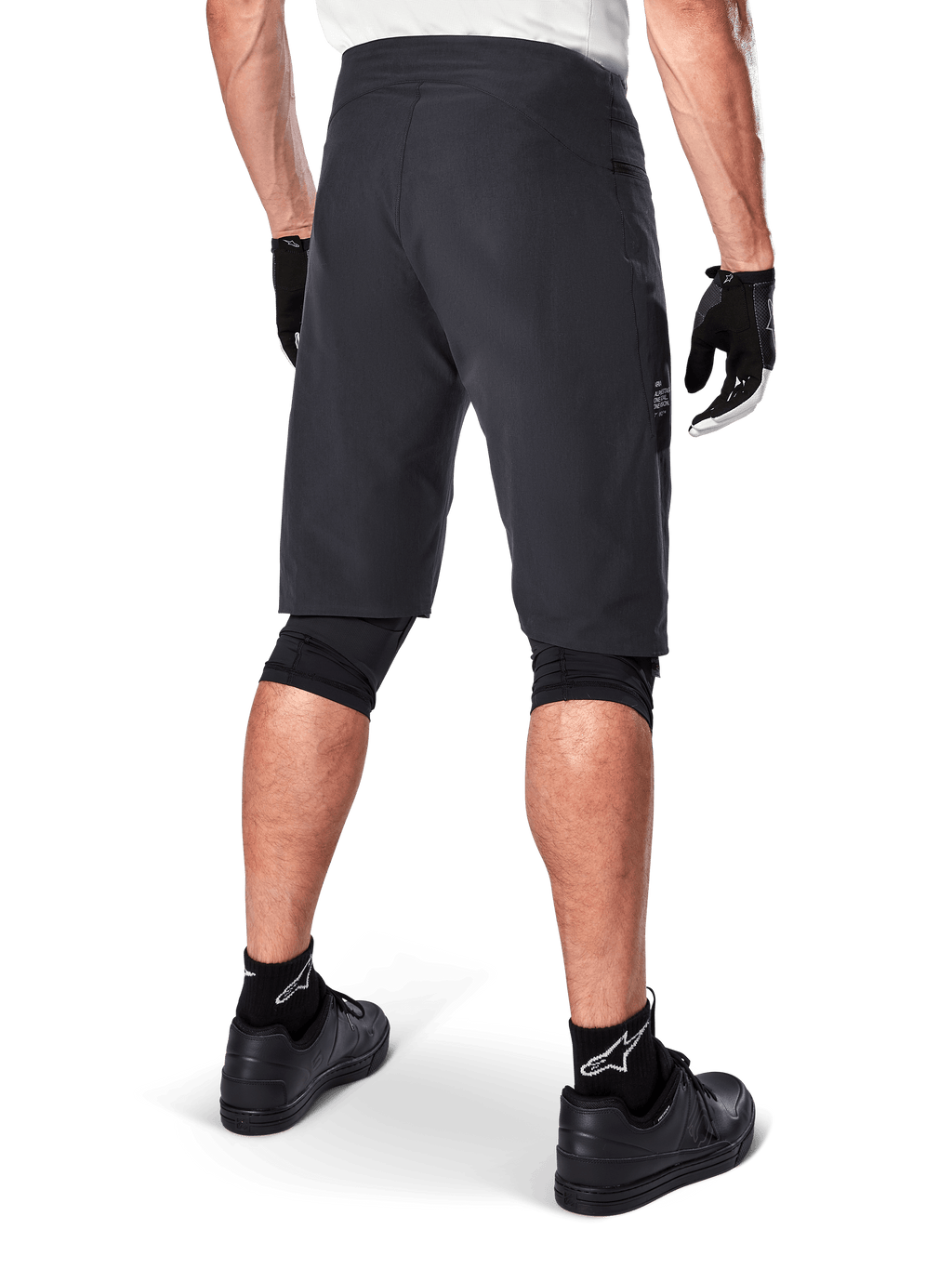 Alpinestars A-Aria Shorts, mountainbike-shorts, sort, set bagfra, viser performance-pasform og rent design, båret med sorte handsker og sokker med det hvide Astars-logo, teknisk cykeltøj til off-road kørsel