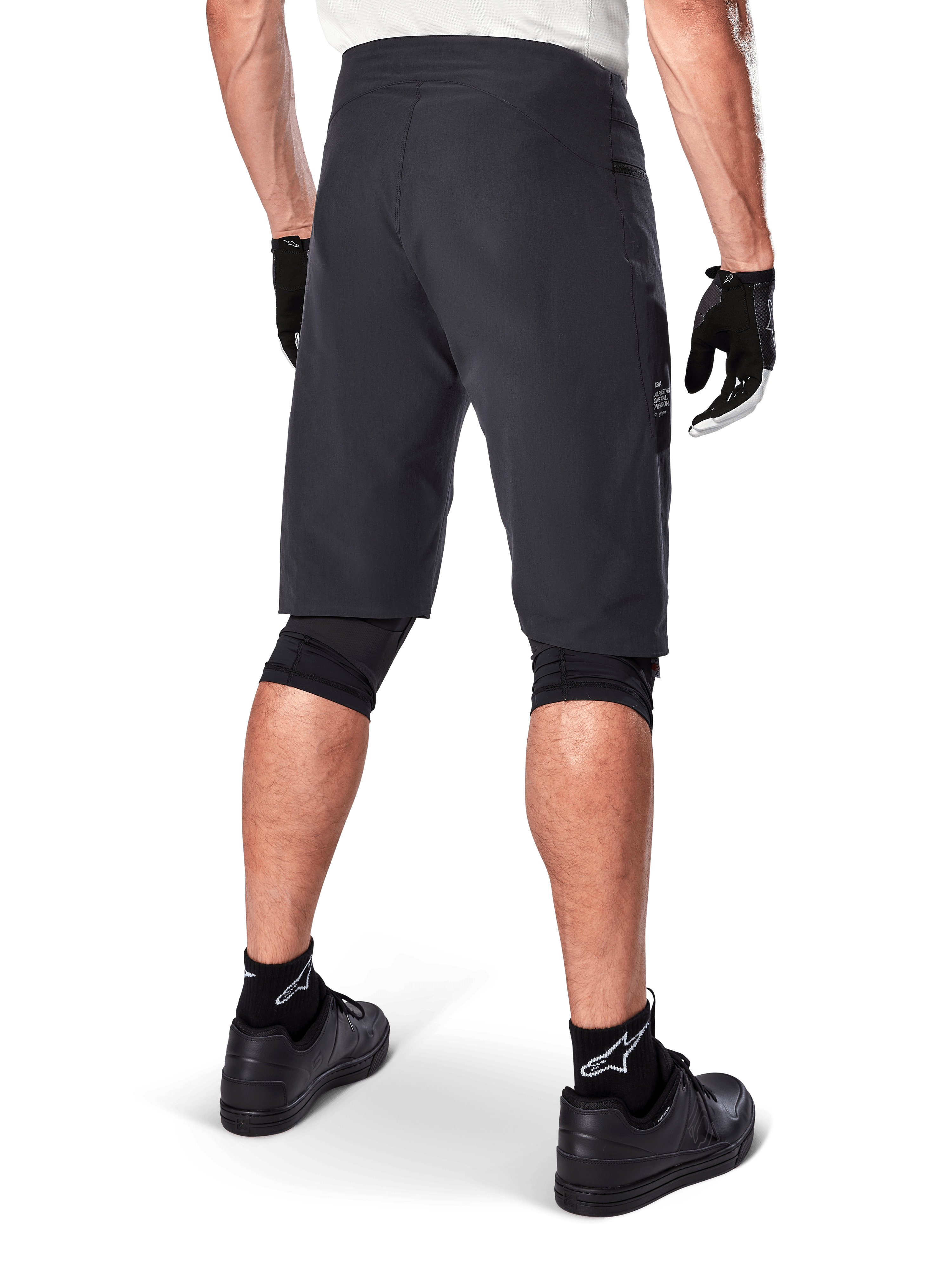 Alpinestars A-Aria Shorts, mountainbike-shorts, sort, set bagfra, viser performance-pasform og rent design, båret med sorte handsker og sokker med det hvide Astars-logo, teknisk cykeltøj til off-road kørsel
