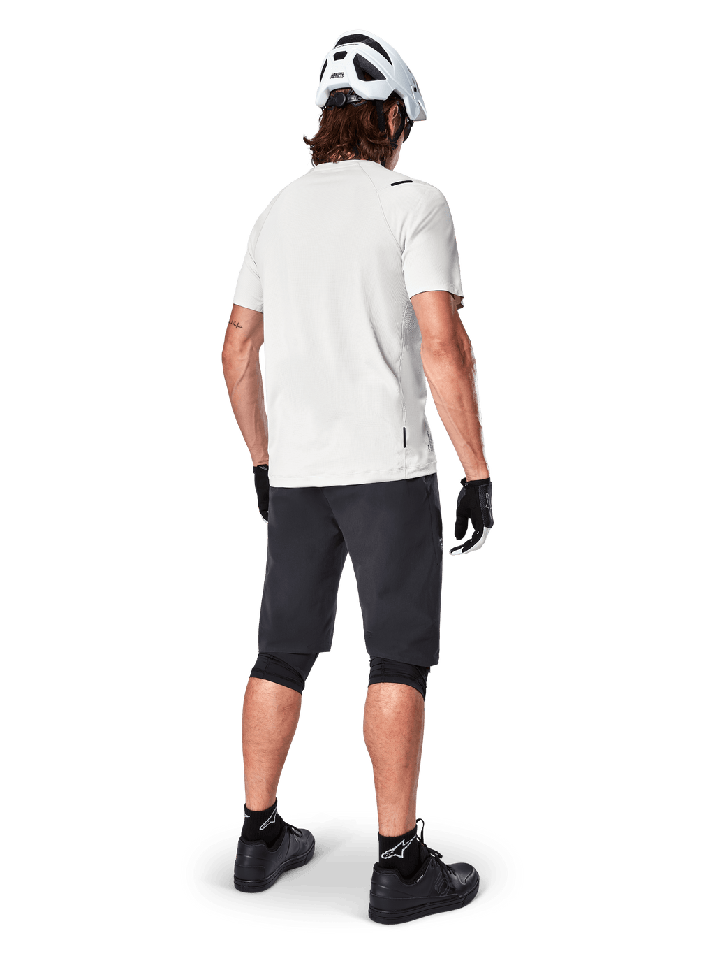 Mountainbiker set bagfra iført Alpinestars A-Aria Shorts i sort, hvid kortærmet performance-trøje, hvid hjelm, sorte handsker og sorte mountainbike-sko, cykeludstyr til trailkørsel