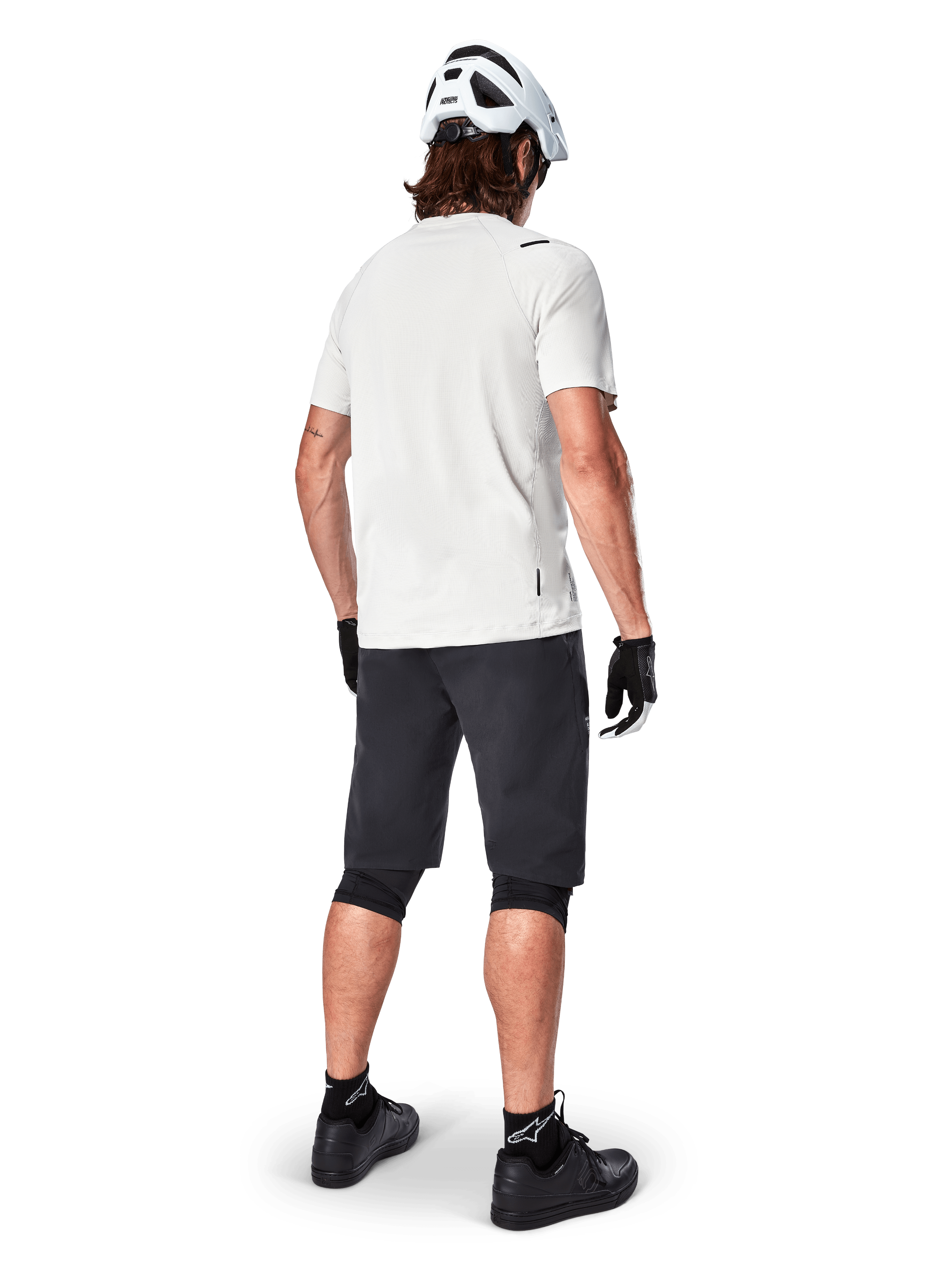 Mountainbiker set bagfra iført Alpinestars A-Aria Shorts i sort, hvid kortærmet performance-trøje, hvid hjelm, sorte handsker og sorte mountainbike-sko, cykeludstyr til trailkørsel