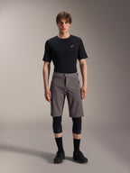 Alpinestars A-Dura Elite Shorts, Dark Gray Mountain Bike Shorts, worn with a black crew neck t-shirt and black knee guards, knee-length performance cycling apparel featuring a front snap closure and durable Cordura fabric.