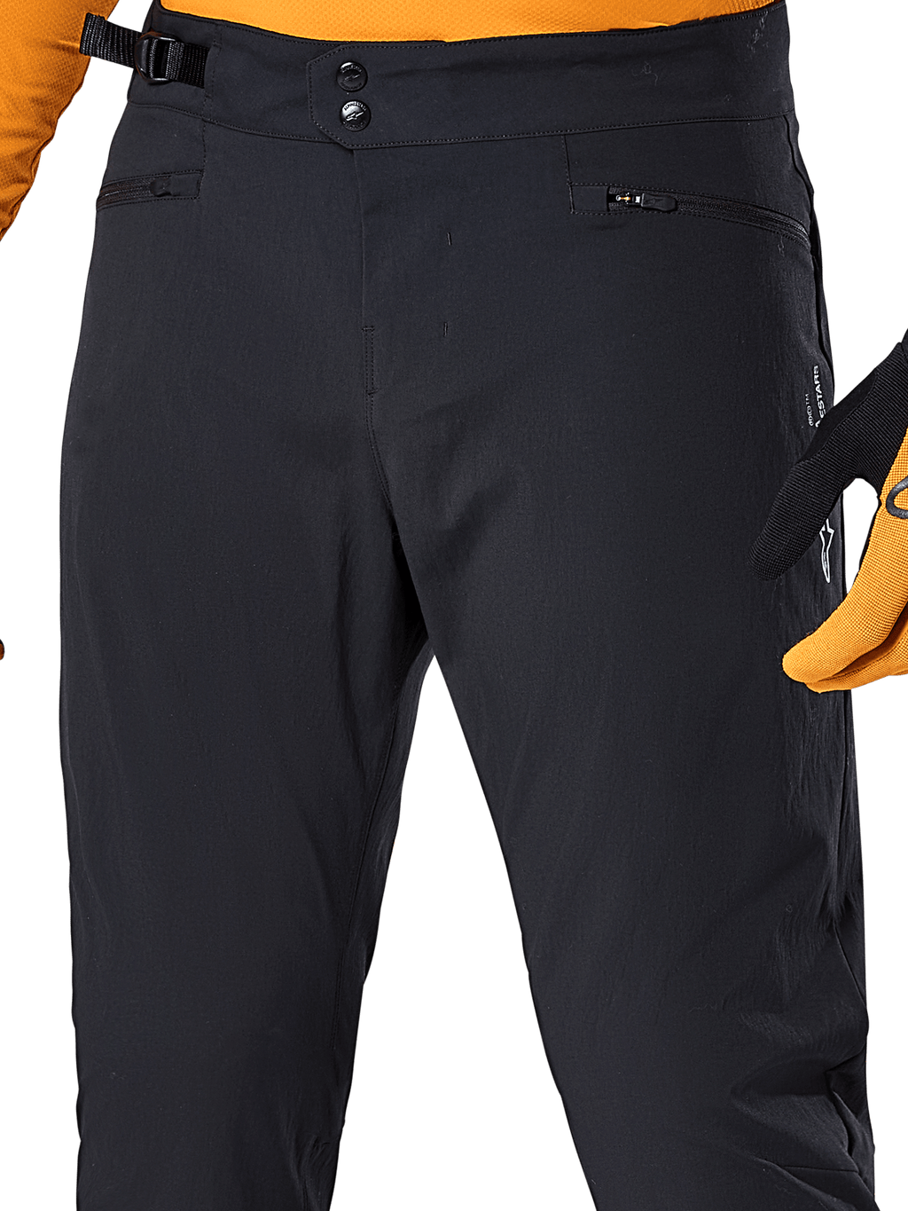 Alpinestars A-Dura bukser, sorte MTB-cykelbukser, nærbillede med dobbelt trykknaplukning i taljen, justerbar sideklemme og lynlåslommer, kombineret med en orange trøje og handsker