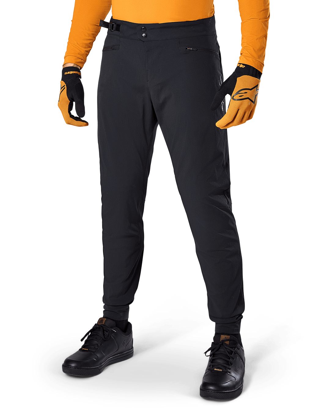 Alpinestars A-Dura bukser, mountainbike-bukser, sorte, sidejustering i taljen og lynlåslommer, båret med orange trøje og handsker, sporty regulær pasform til MTB-kørsel