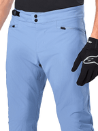 Alpinestars A-Dura bukser, MTB-cykelbukser, Infinity Blue, nærbillede af taljen med dobbelt trykknapslukning og justerbar sideklemme, lynlåslommer, båret med sorte Alpinestars-handsker