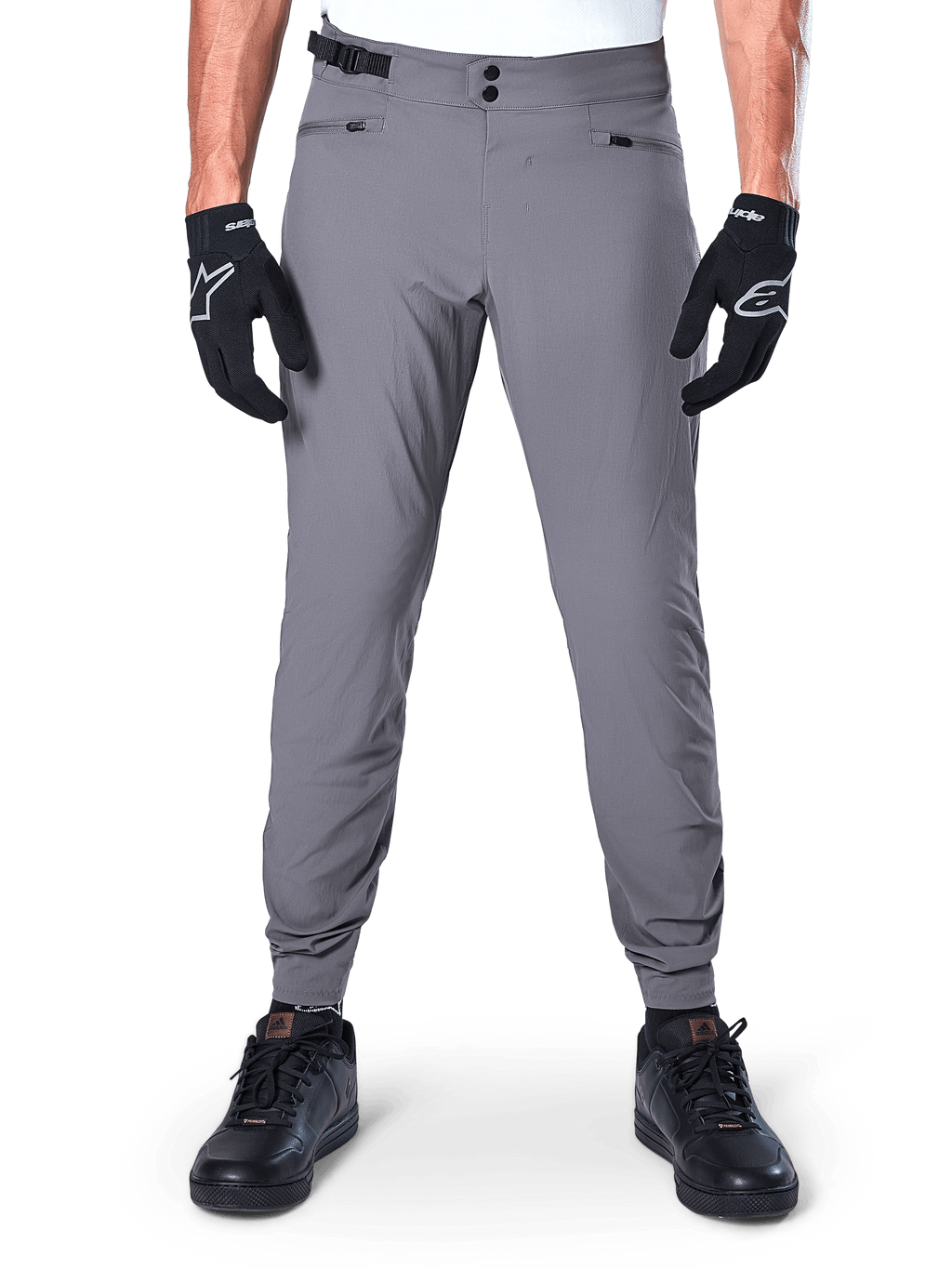 Alpinestars A-Dura bukser, mørkegrå mountainbike-bukser, set forfra båret med sorte handsker og sorte sneakers, med dobbelt trykknaplukning i taljen, lynlåslommer og elastiske manchetter, holdbart cykeltøj til terrænkørsel