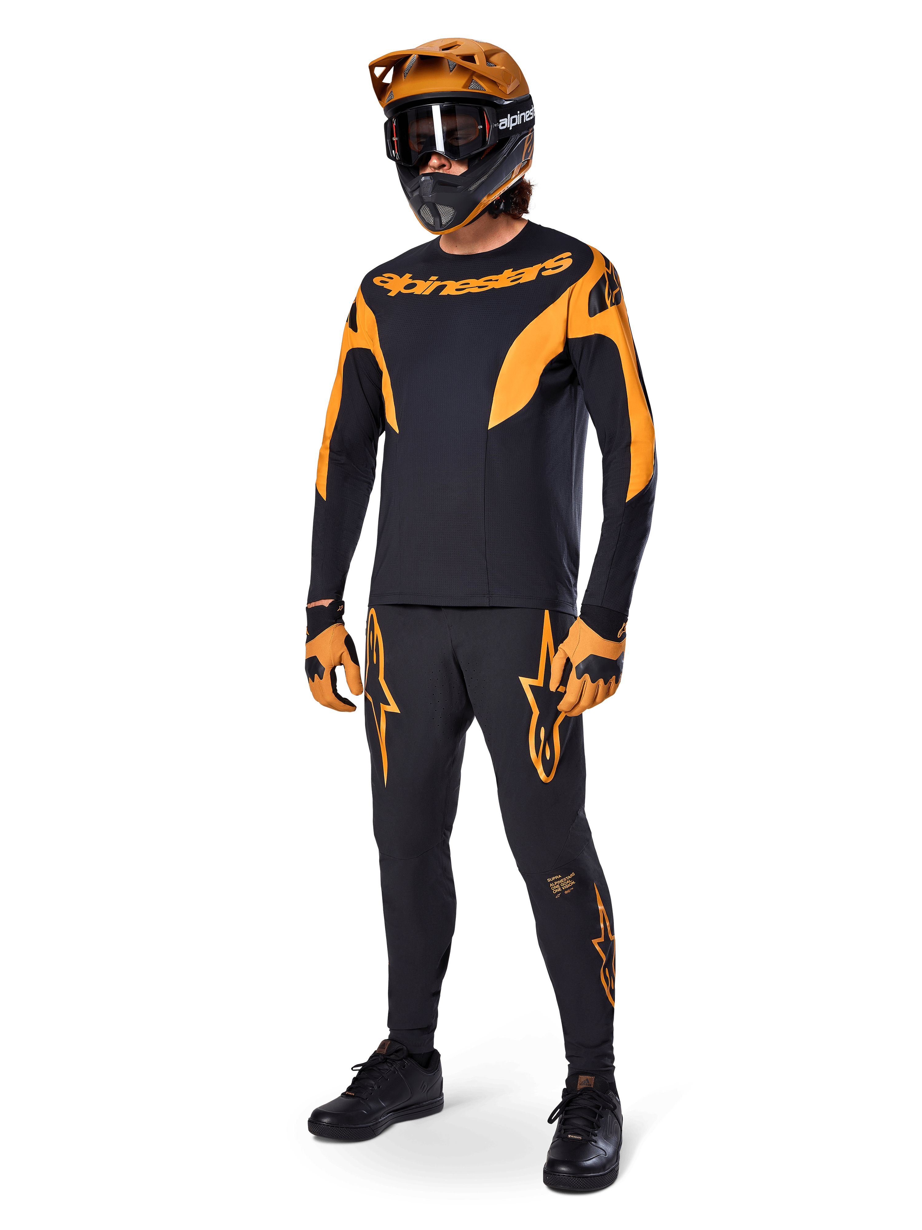 Mountainbike-rytter iført komplet racerudstyr, Alpinestars A-Supra Race bukser i sort med orange detaljer, matchende sort og orange langærmet jersey, orange hjelm med sorte goggles, orange og sorte handsker og sorte sko, professionelt MTB-racersæt