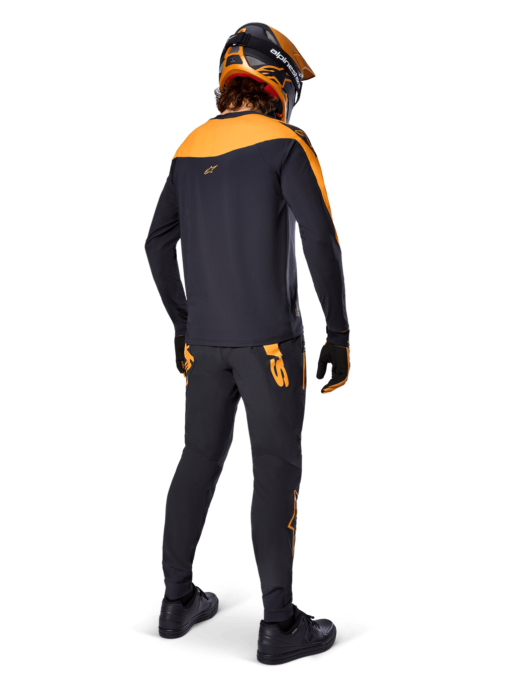 Alpinestars A-Supra Race bukser, MTB racing-bukser, sort med orange logoer, set bagfra på en rytter iført matchende sort og orange jersey, hjelm og handsker, hvilket fremhæver det MX-inspirerede ordmærke på bagstykket og en performance-pasform til tekniske spor.