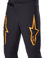Alpinestars A-Supra Race-bukser, sorte MTB-cykelbukser med store orange stjernelogoer, ratchet-lukning foran og laserperforerede ventilationshuller, performance-orienteret teknisk design