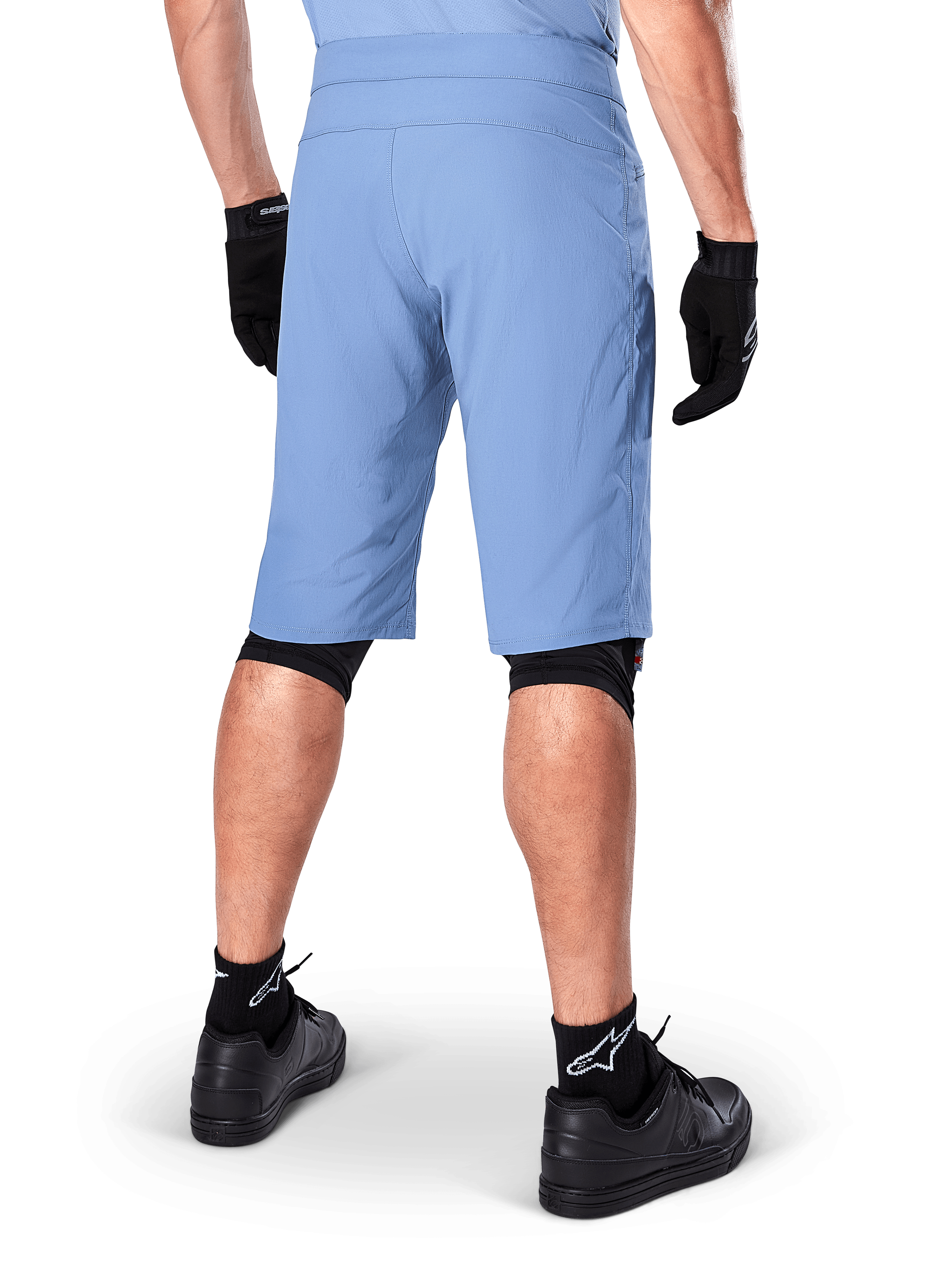 Alpinestars A-Dura Shorts, Infinity Blue mountainbike-shorts, set bagfra, kombineret med sorte handsker, knæbeskyttere og sorte sokker med hvidt stjerne-logo, slidstærkt strækmateriale til off-road cykling