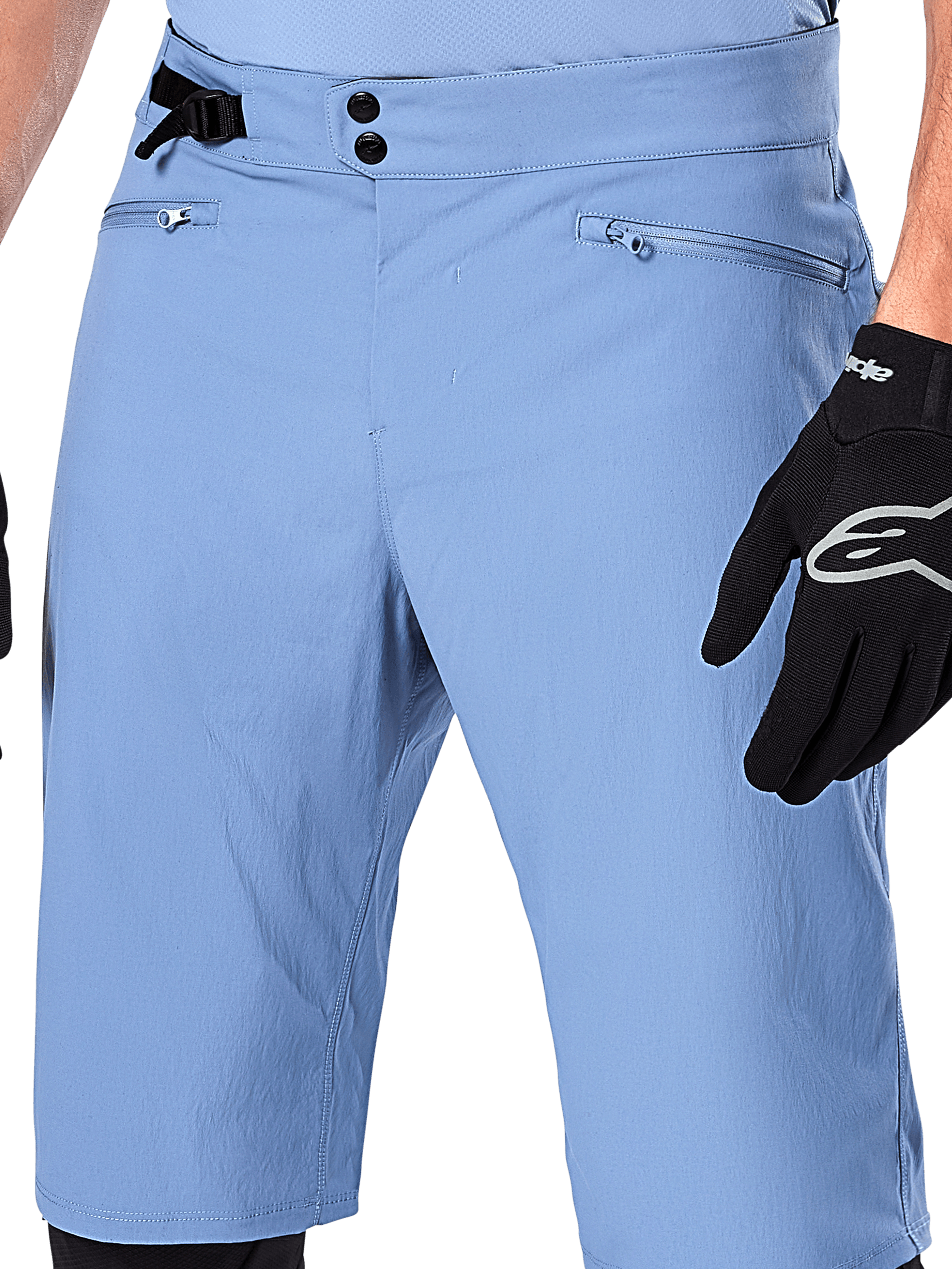 Alpinestars A-Dura Shorts, Infinity Blue mountainbike-shorts, nærbillede af taljen med dobbelt snaplukning, justerbar sidejustering og lynlåslommer med mesh-foring, båret med en sort Alpinestars-handske