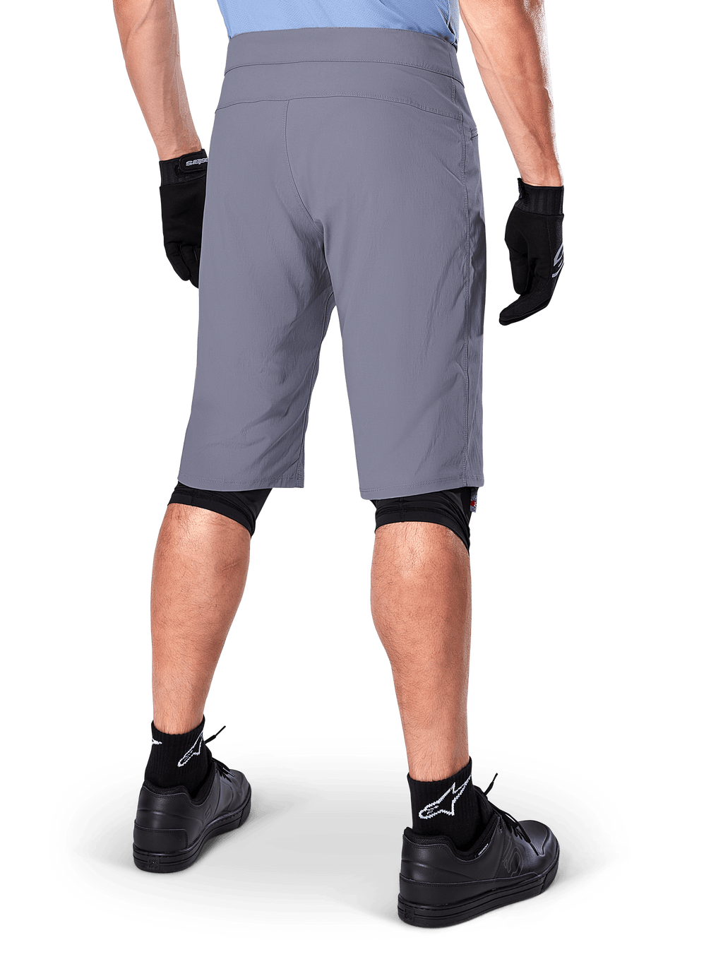 Alpinestars A-Dura Shorts, mørkegrå mountainbike-shorts, set bagfra på en rytter, bæres med sorte handsker, sorte knæ-liners og sorte sokker med Alpinestars-logo, holdbar konstruktion til terrænkørsel